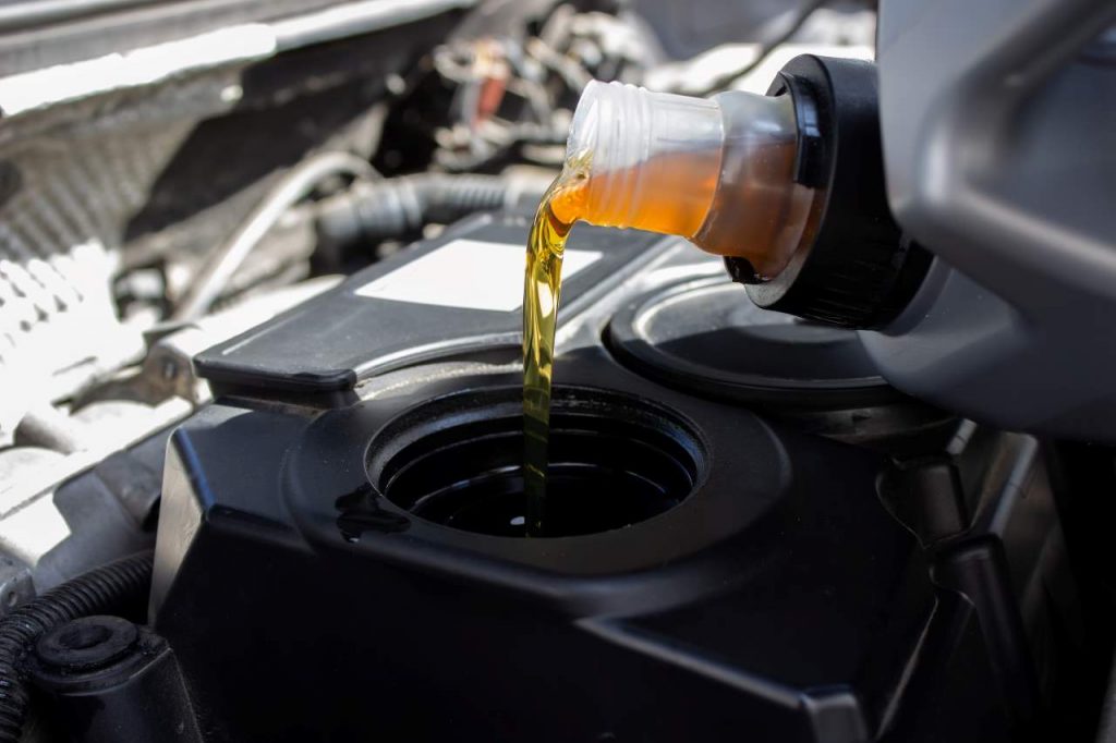 engine oil leak repair, a hand pouring oil quality into the engine