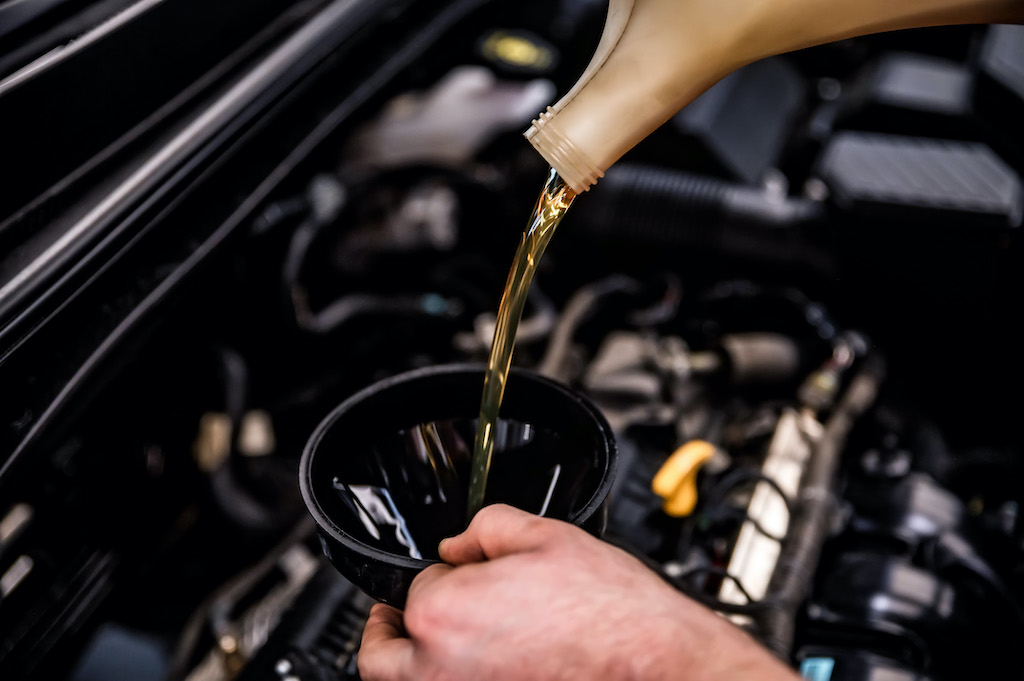 Car engine oil types, pouring engine oil with a funnel.