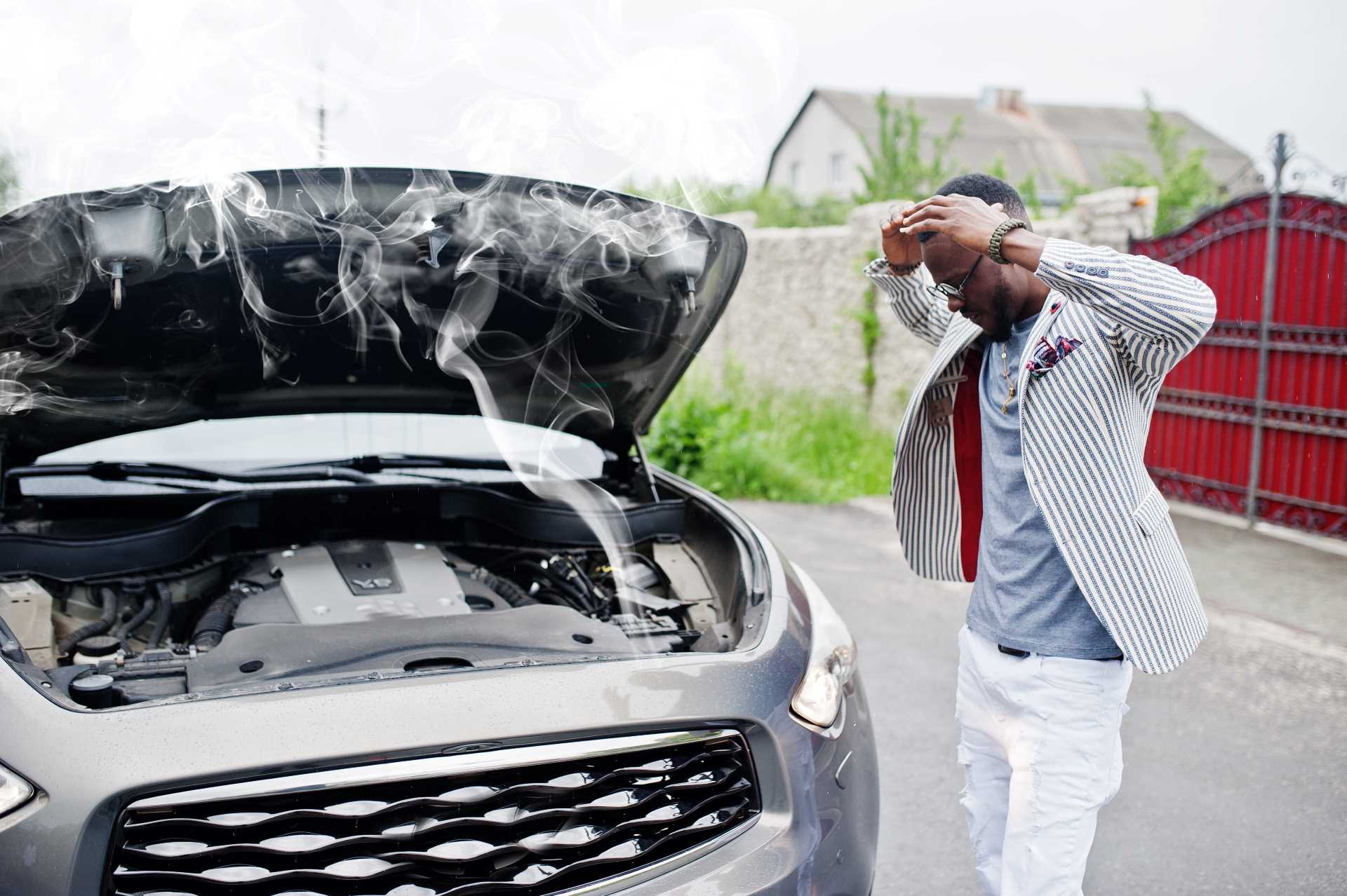 car overheating, man standing stressed beside overheated car